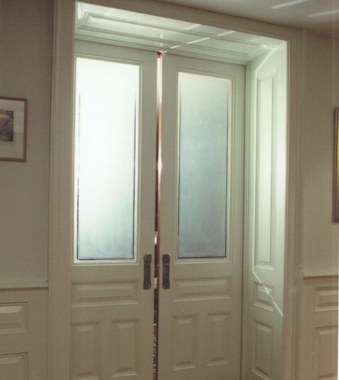 Pocket Doors with etched glass and wall paneling throughout the room